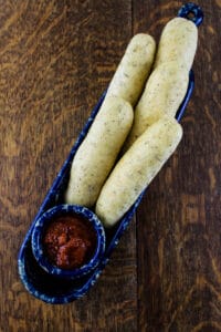 Breadsticks and marinara sauce on blue plate