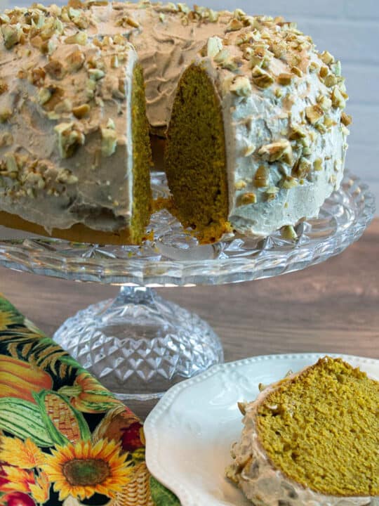 pumpkin poundcake on cake stand, one slice on white plate.