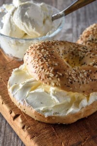 bowl of cream cheese and bagel on wooden cutting board