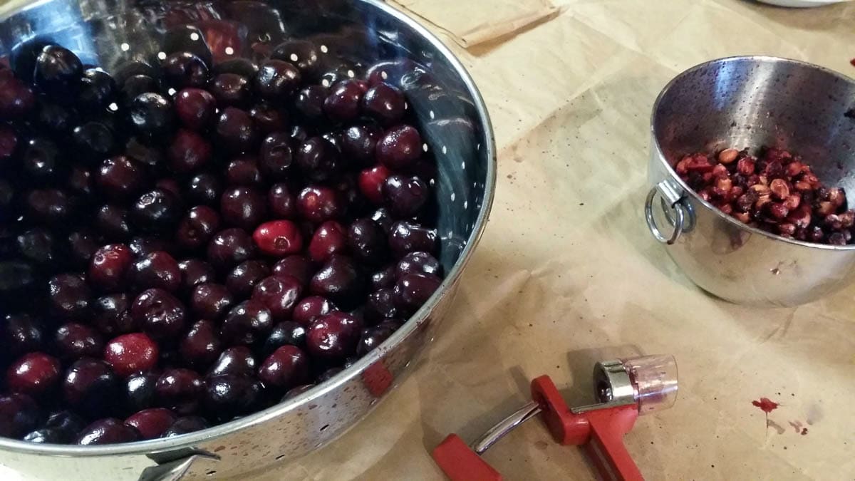 cherries in colander with cherry pitter for canning cherry pie filling