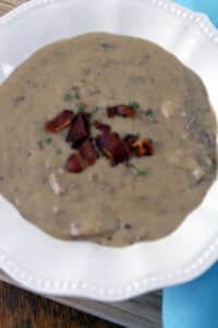 Beef and Bacon Chowder in white bowl with blue napkin.