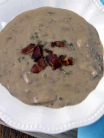 Beef and Bacon Chowder in white bowl with blue napkin.