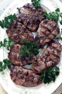 Grilled lamb chops with parsley on white platter.
