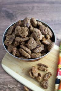 Candied pecans in bowl on cutting board.