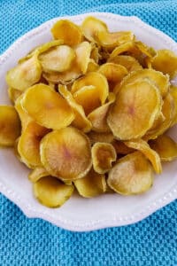 Dehydrated potato slices in white bowl on blue towel.