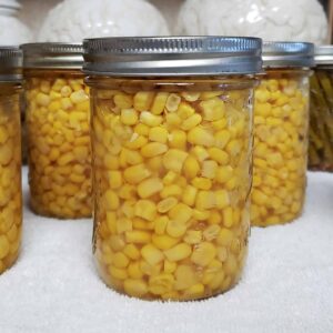 Jar of canned corn on white towel.