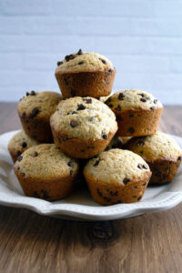 Chocolate chip muffins on a white plate on a wooden table.