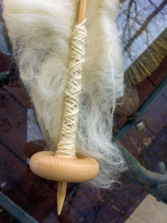 DIY drop spindle with roving attached.