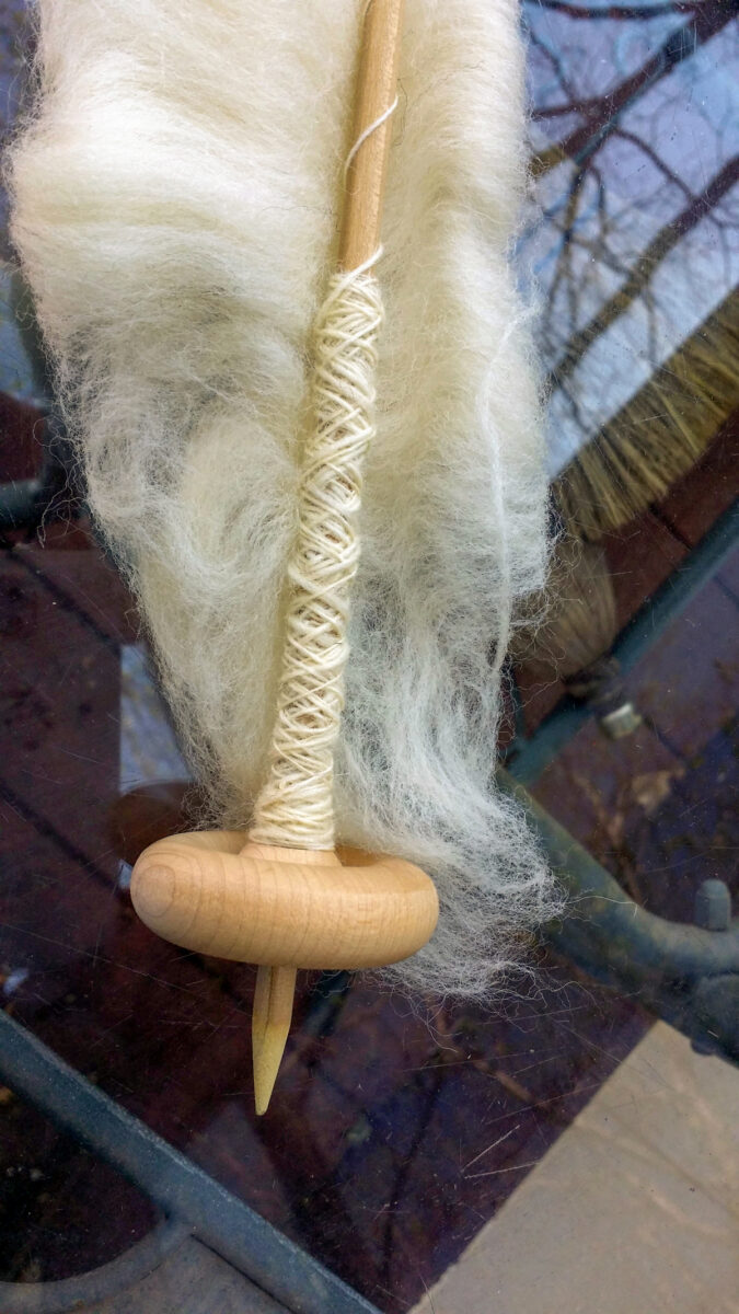 DIY drop spindle with roving attached.